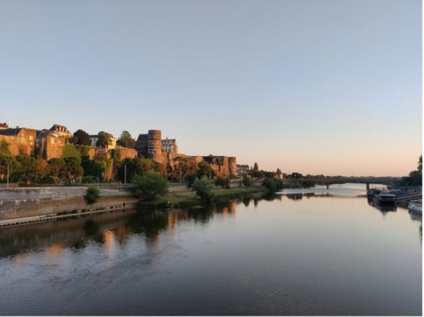 Vue sur la rivière Maine à Angers au coucher du soleil avec le château d’Angers et les quais arborés