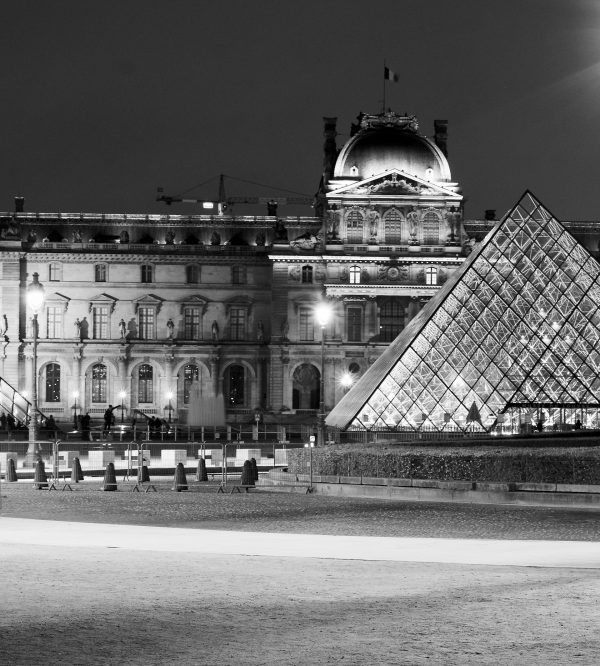 Vue nocturne en noir et blanc du musée du Louvre à Paris avec la pyramide illuminée au premier plan