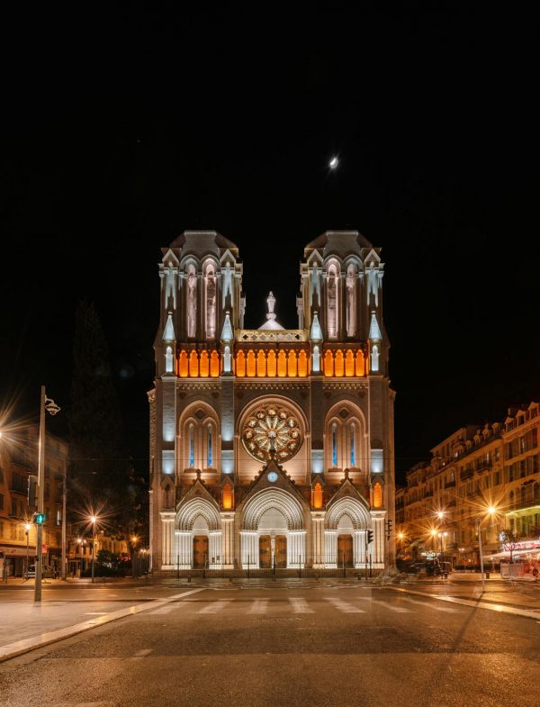 Façade illuminée de la Basilique Notre-Dame de l’Assomption à Nice photographiée de nuit avec rosace et deux tours néogothiques