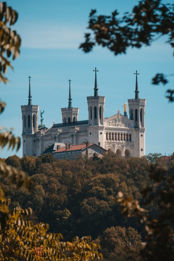 Basilique Notre-Dame de Fourvière à Lyon, édifice religieux dominant la ville sur la colline de Fourvière, entouré de verdure sous un ciel bleu