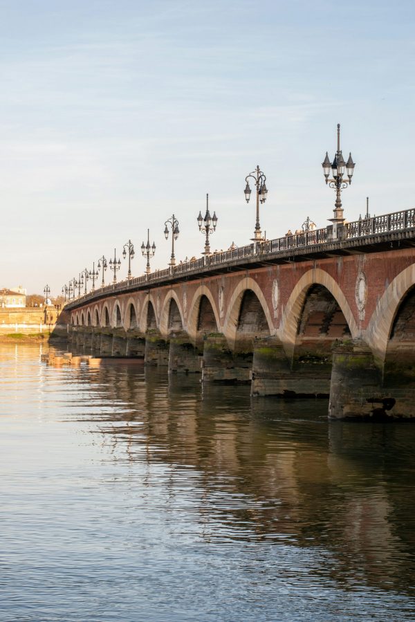 Pont de Pierre à Bordeaux avec arches en pierre et réverbères, traversant la Garonne par temps clair