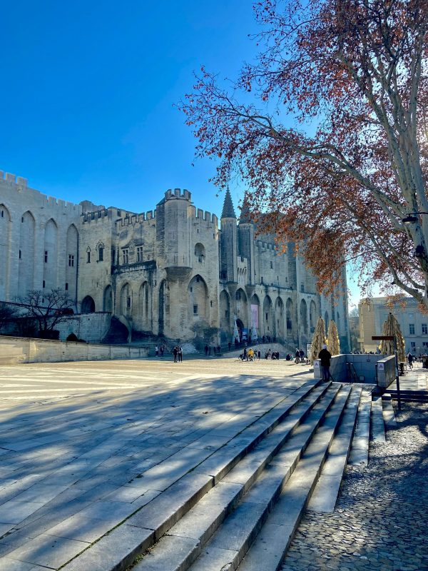Façade du Palais des Papes à Avignon, monument gothique médiéval sur une grande place sous un ciel bleu