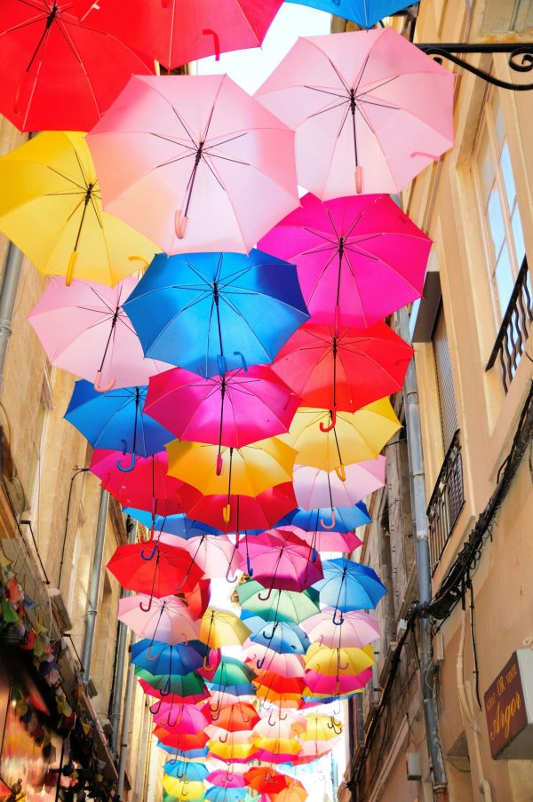 Rue étroite d’Avignon décorée de parapluies colorés suspendus, installation artistique dans le centre historique