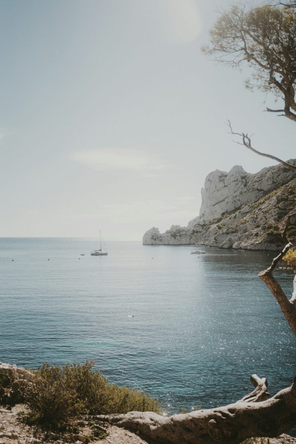 Calanque près de Marseille avec falaises calcaires, mer Méditerranée calme et voiliers au mouillage sous un ciel clair