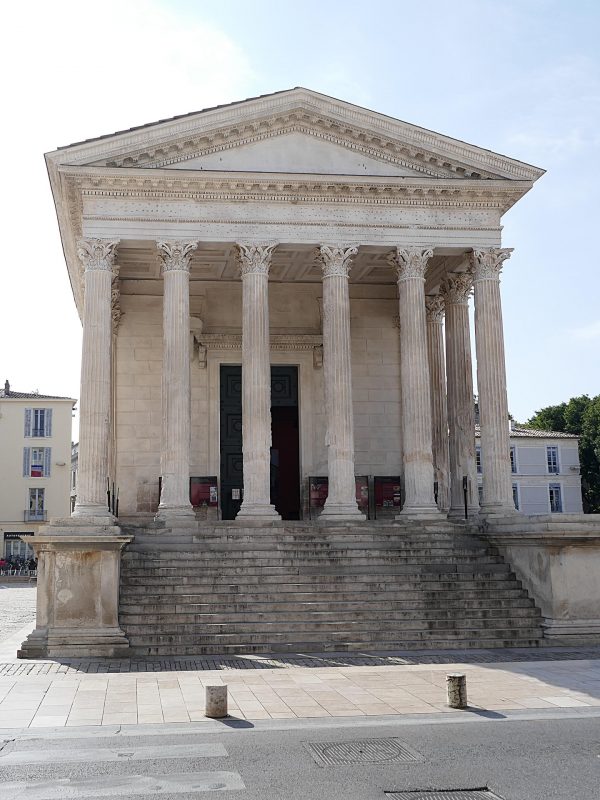Façade de la Maison Carrée de Nîmes, temple romain aux colonnes corinthiennes, vue de face sous un ciel bleu